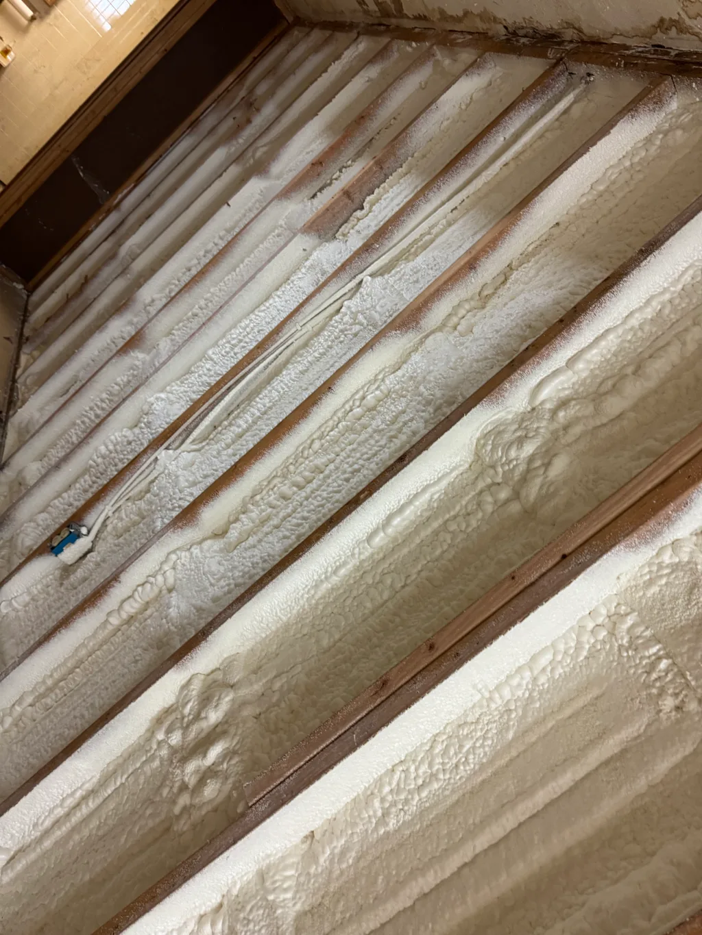 Textured cream foam along a low sloping roof with a cable running across the bays