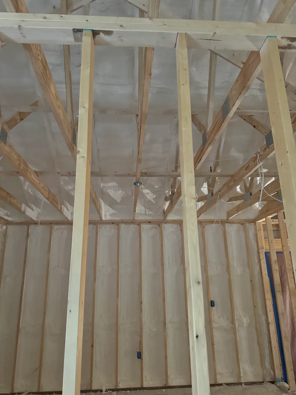 Fresh ceiling framing and collar ties below a pale foamed roof in a new build