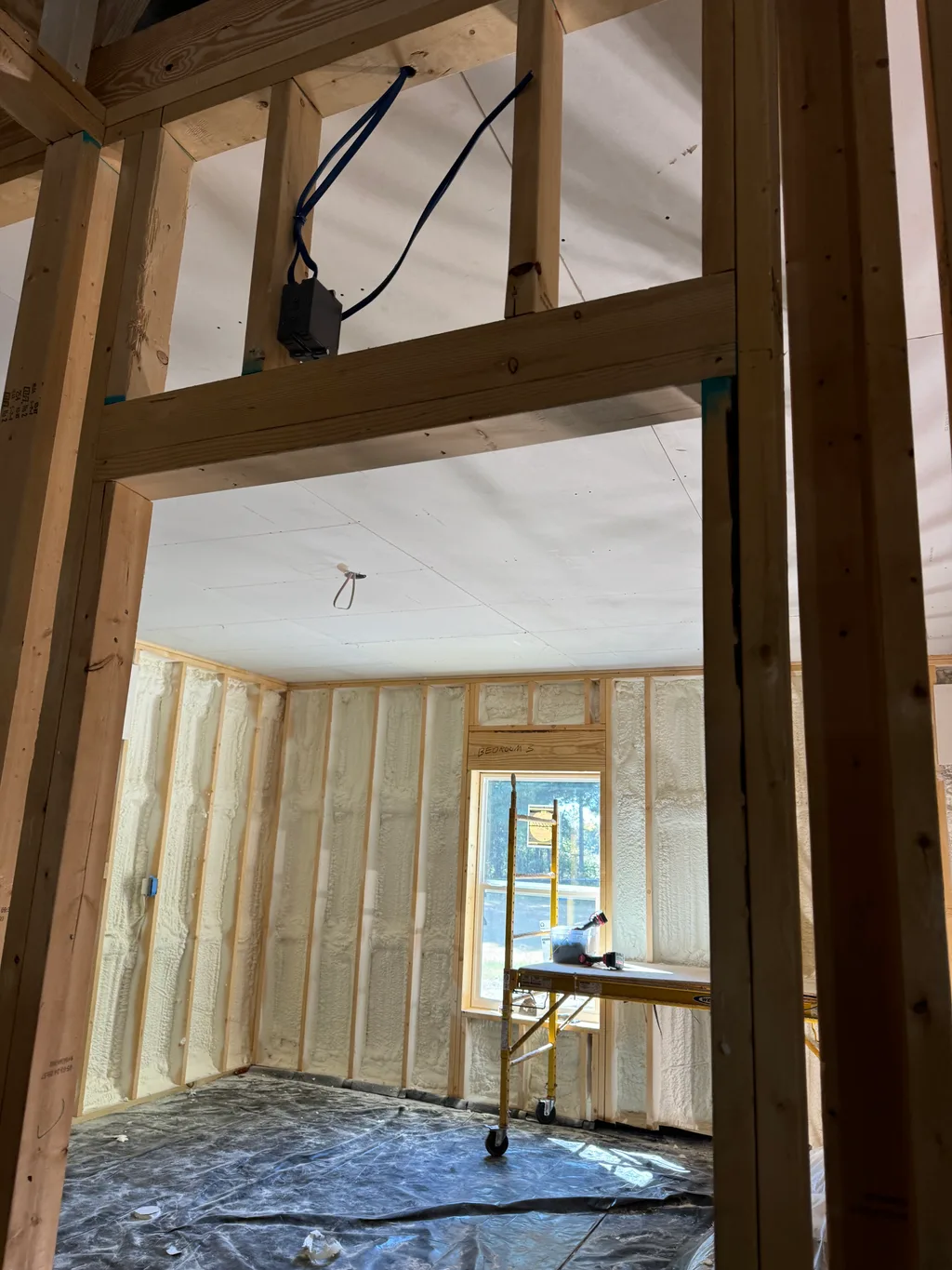 Timber framed opening looking through into a foamed room with a bright window beyond