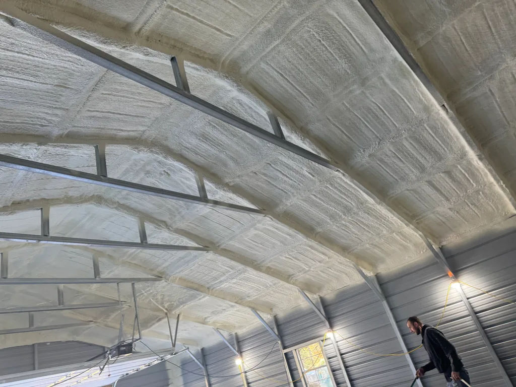 Person walking through a steel building below a fully foamed curved roof deck