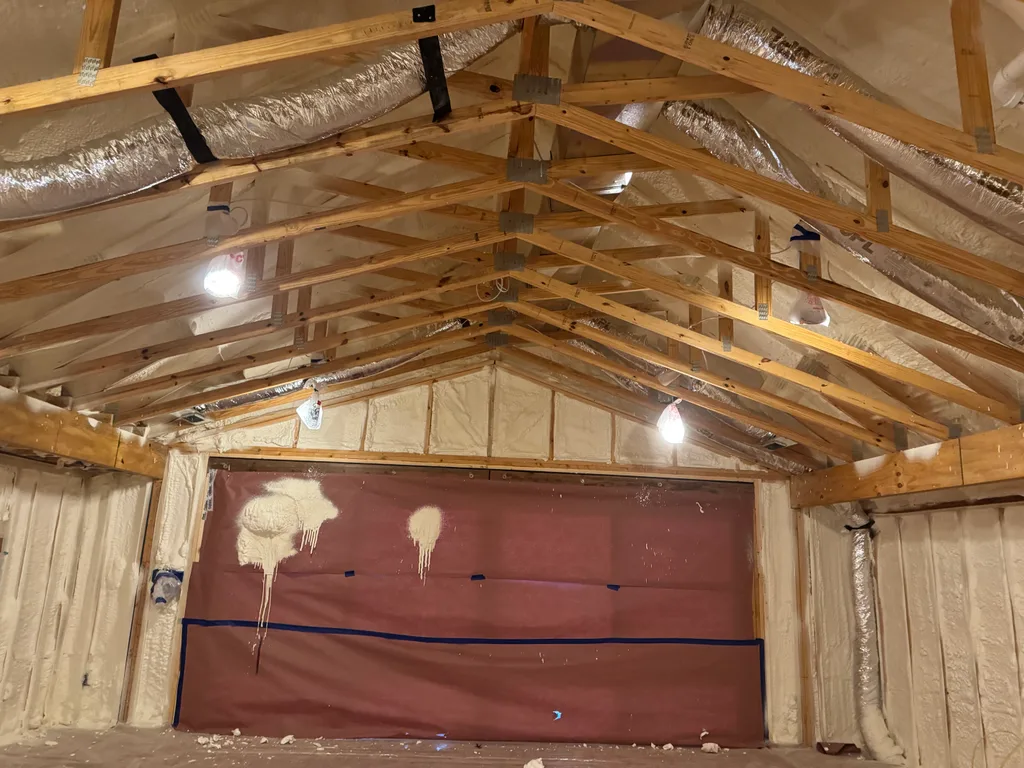 Foamed walls and timber trusses around a dark red membrane panel on the end wall