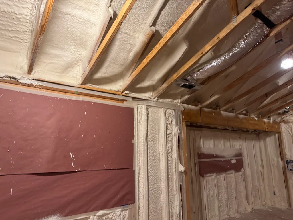 Foamed ceiling and joists meeting red membrane panels on the wall below