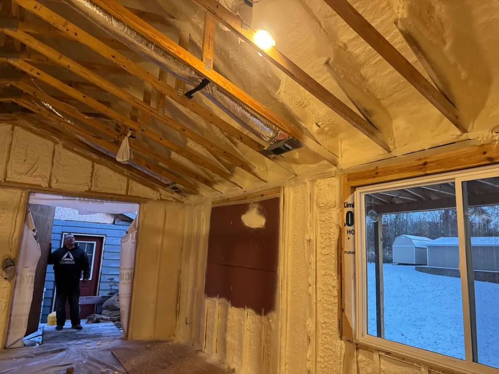 Foamed room with a doorway open to snow outside and a person standing beyond