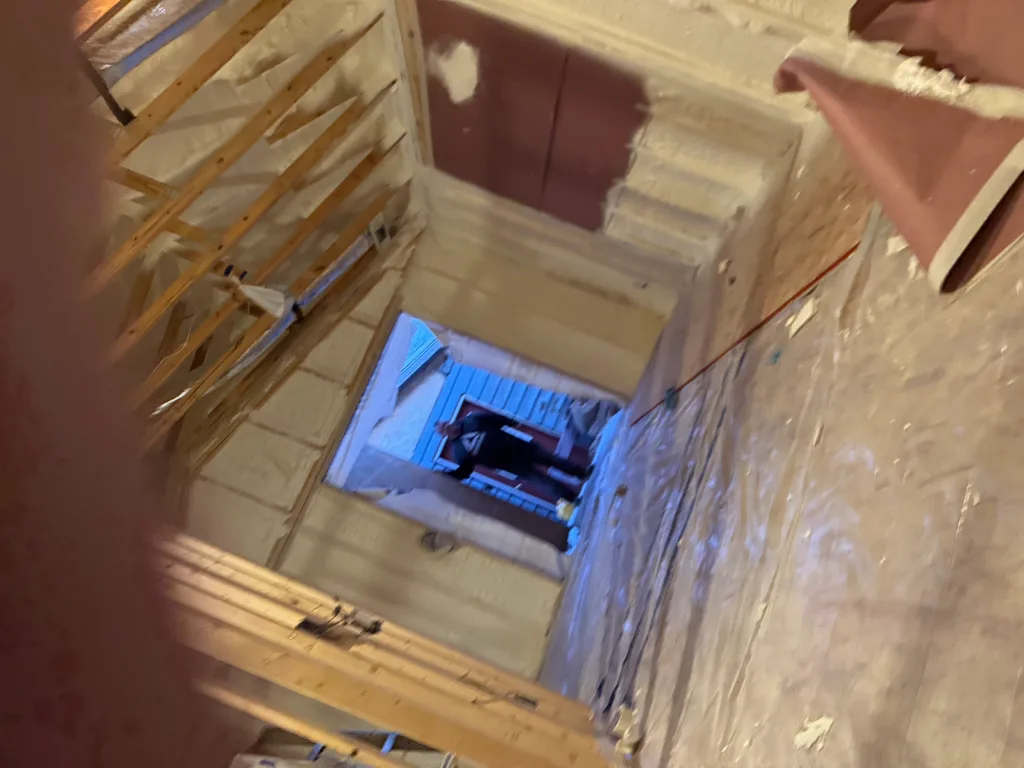 Dim interior with plastic sheeting, foamed framing and light through a far opening