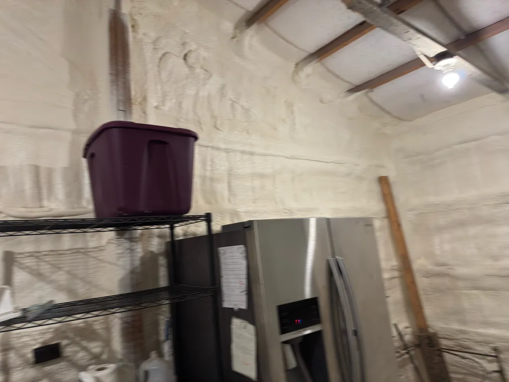 Foamed walls and roof of a workshop with a fridge and wire shelving against the wall