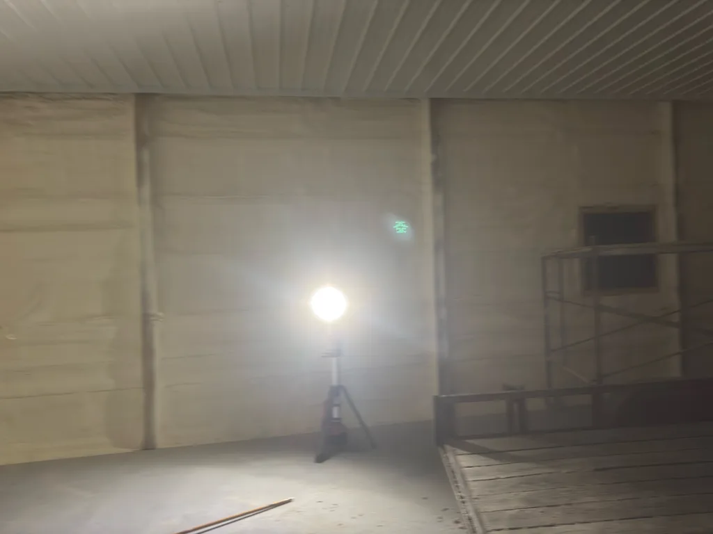 Work light on a stand lighting the cream foamed walls of an empty finished room