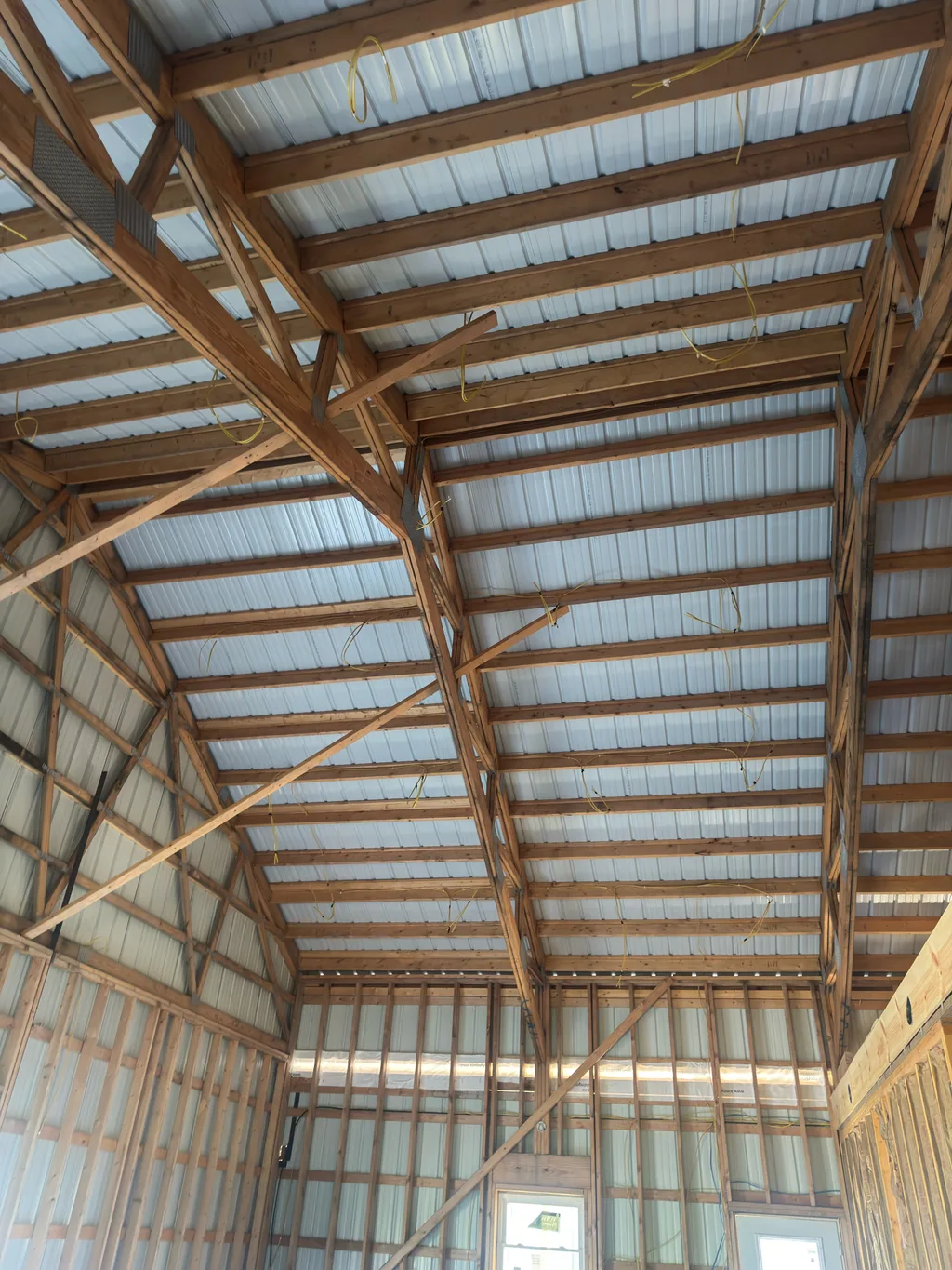 Bare framing and diagonal bracing below a steel roof deck in an open bay