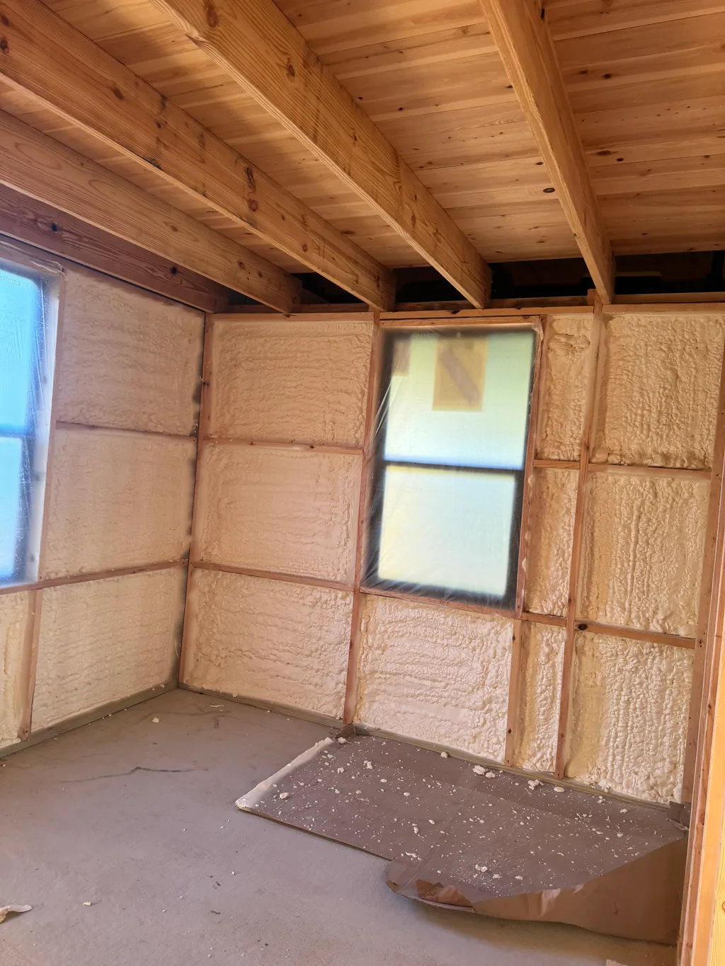 Foamed walls below a timber plank ceiling with a window and foam trimmings on the floor