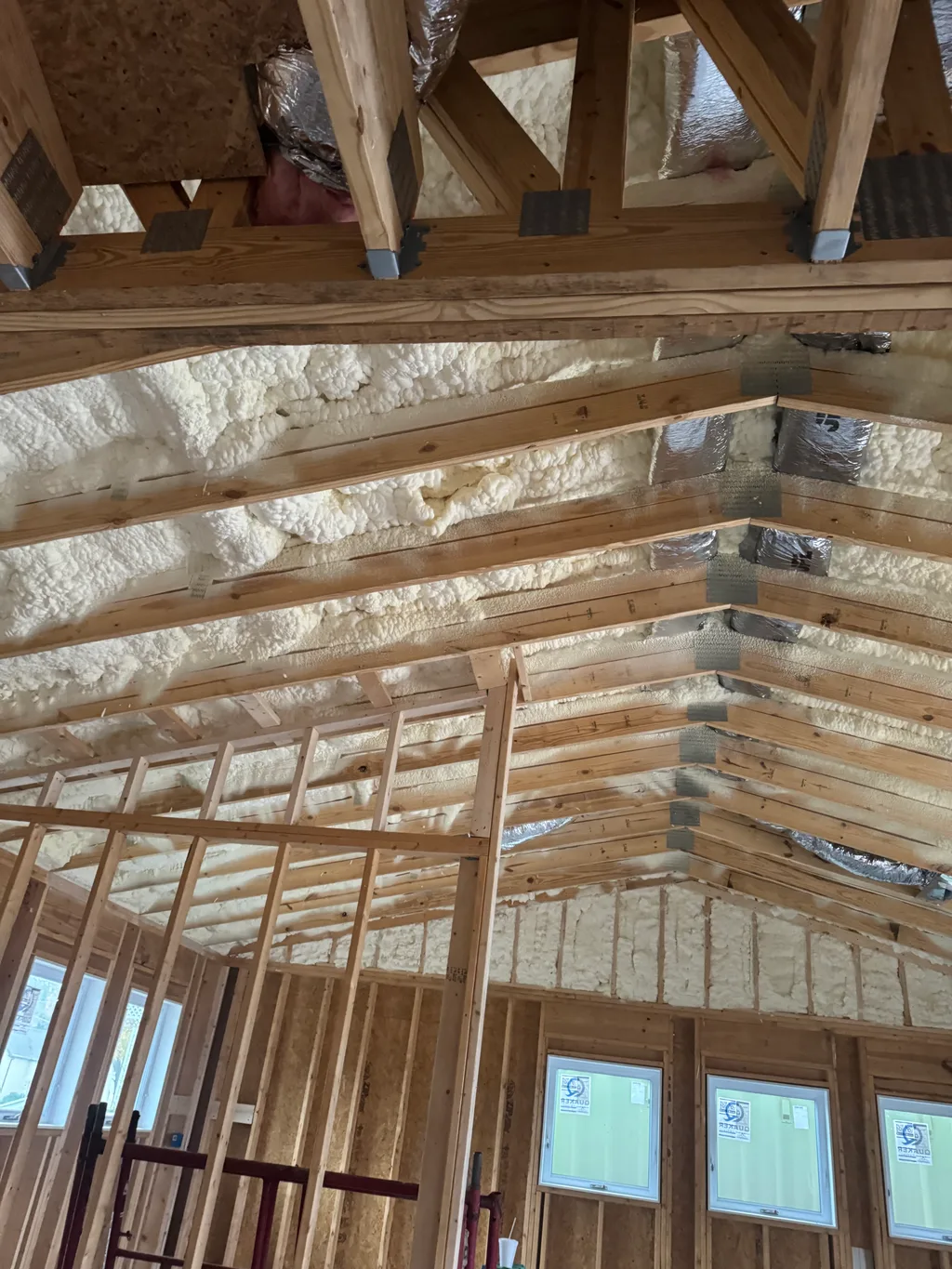 Foamed roof above new trusses and framing with foil ducts and a row of windows